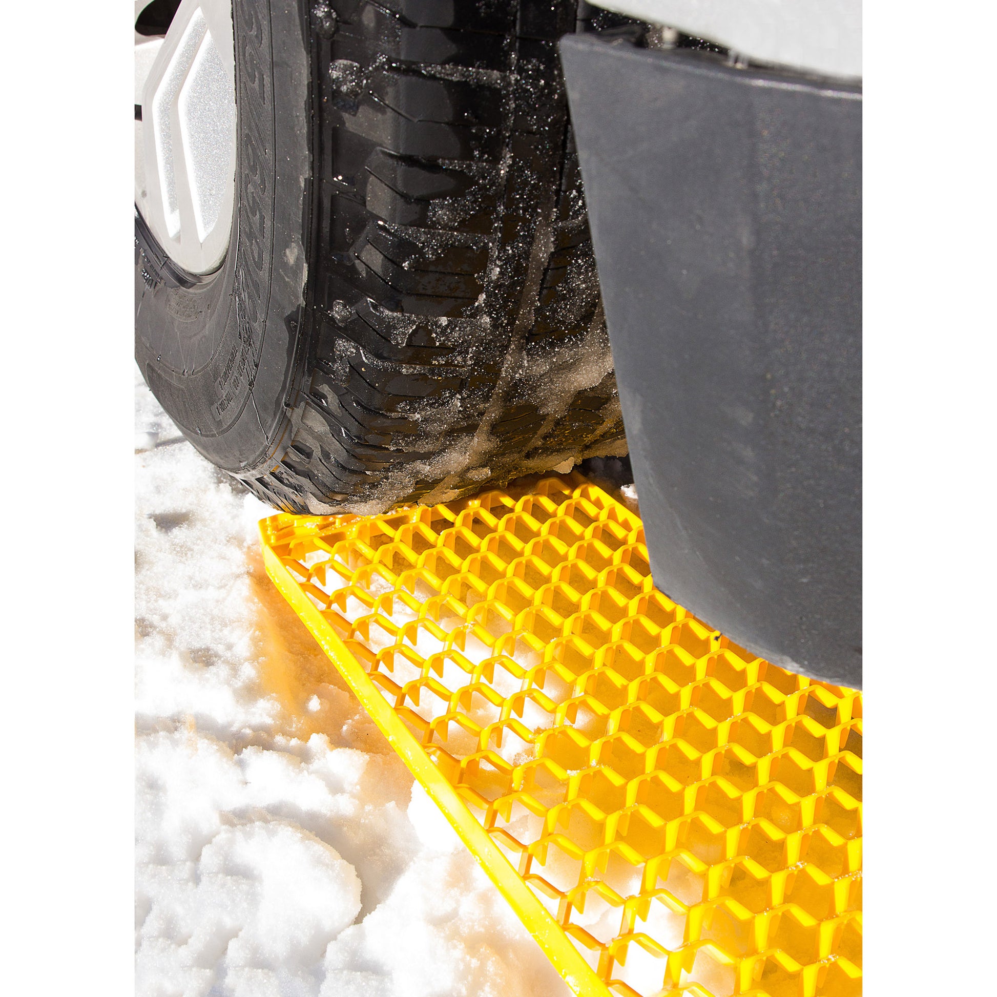 A car tire is on a SubZero® GripTrax™ Traction Tool in the snow, providing extra grip for winter emergencies.