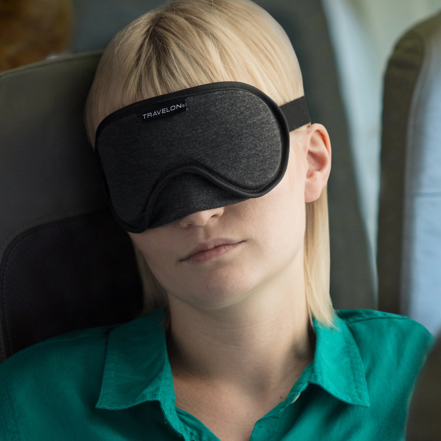 A person in a green shirt rests and blocks light wearing a Travelon Cooling Gel Eye Mask.