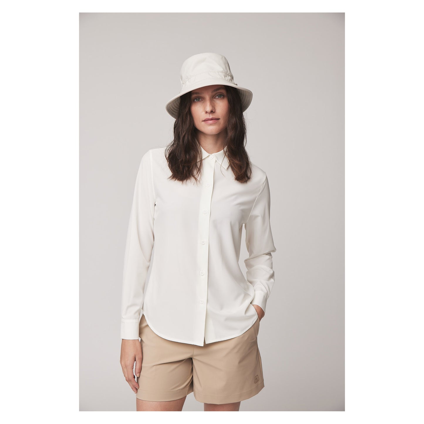 Woman in a white button-up, beige shorts, and Tilley LTM1 Airflo® Bucket Hat stands against a plain background.