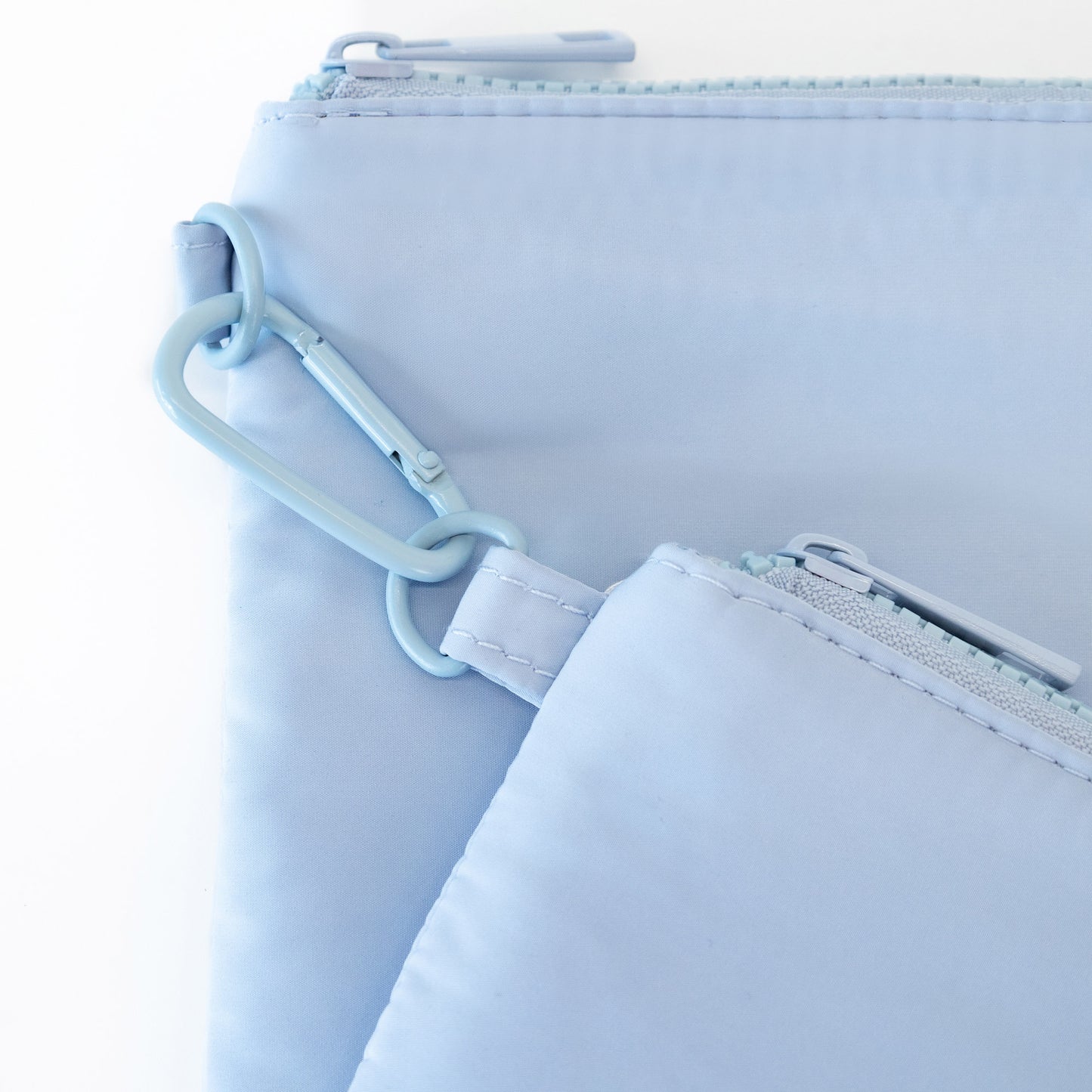 Close-up of two MyTagAlongs Organization Pouches in light sky blue, connected by a blue carabiner clip.