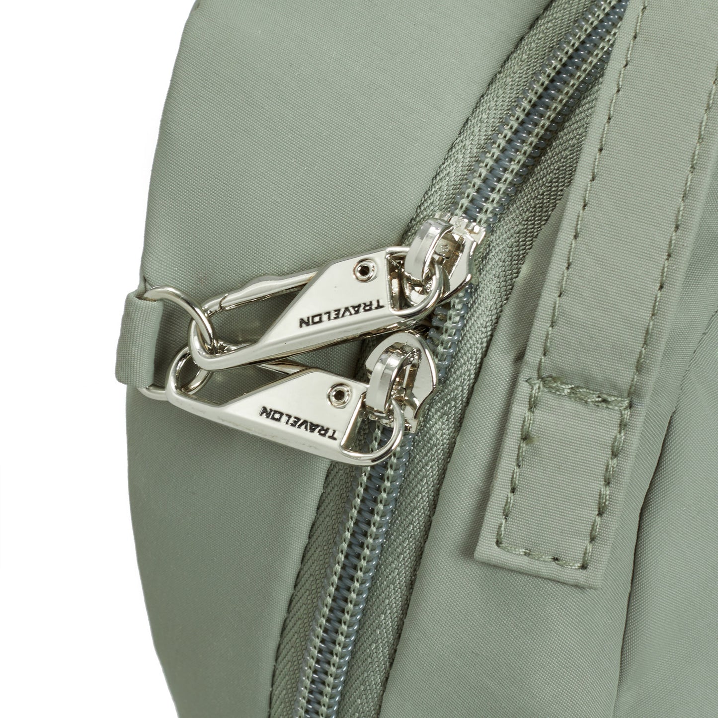 Close-up of a Travelon Roam moss green nylon bag with silver engraved zippers.