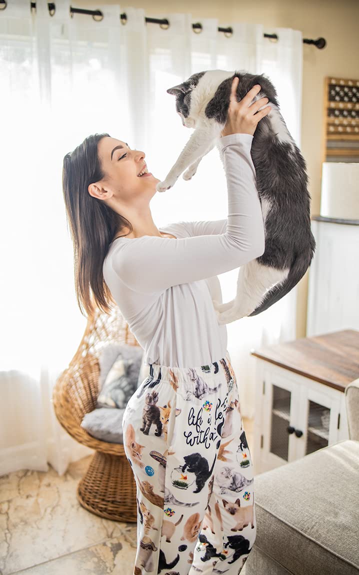 Woman smiles holding a cat, wearing Brief Insanity "Life is Better With a Cat" lounge pants.