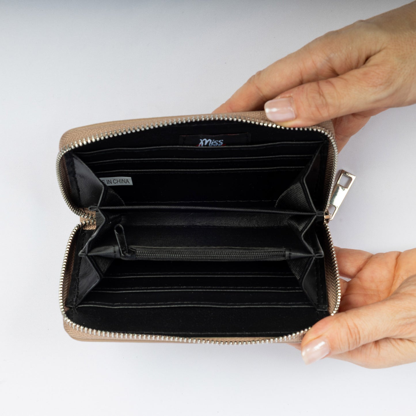 A person holds open the Miss Caprice Zip Around Wallet, showing its multiple compartments and card slots.
