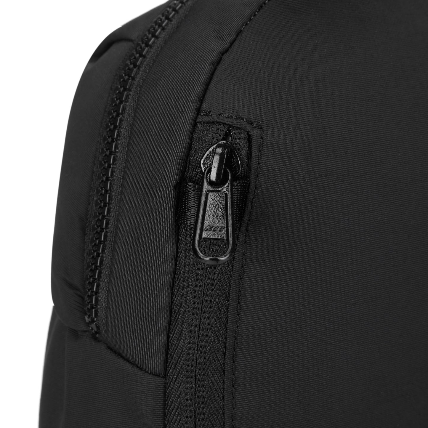Close-up of a Pacsafe CX 8L backpack corner featuring black regenerated nylon and a visible zipper.