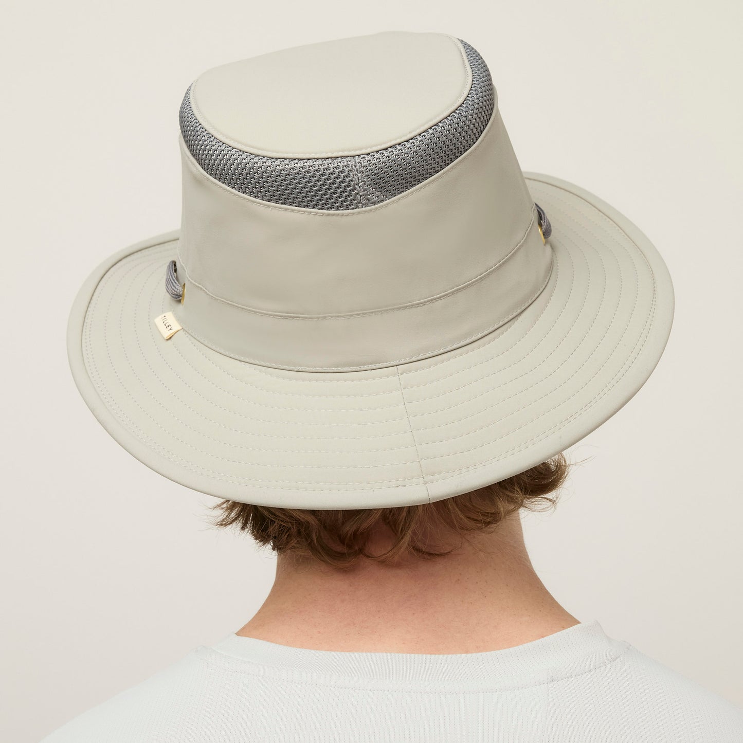 Person with light brown hair in a light gray Tilley LTM5 Airflo® Hat with mesh, viewed from behind.