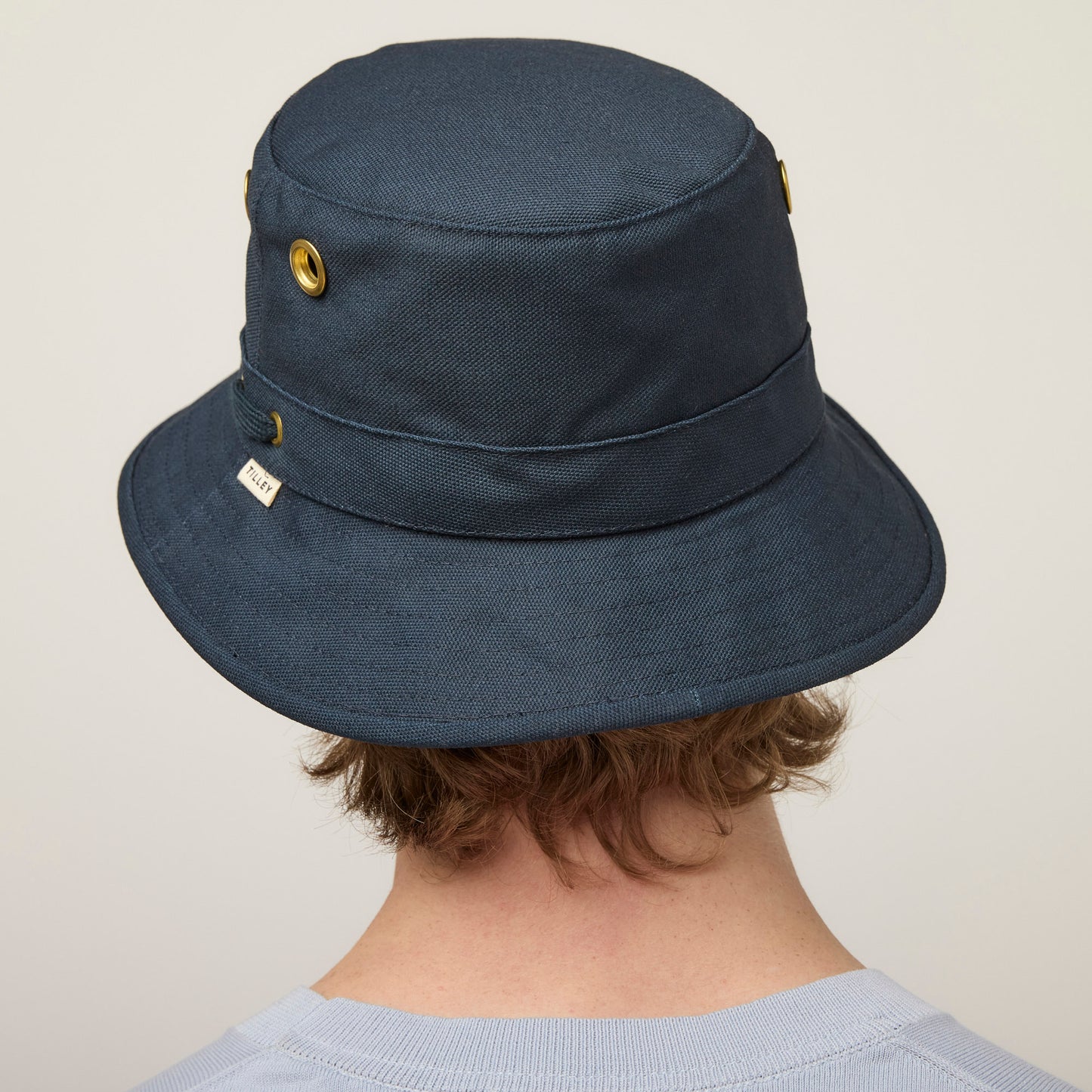 A person wearing the Tilley T1 Iconic Bucket Hat in dark blue cotton, seen from behind against a plain background.