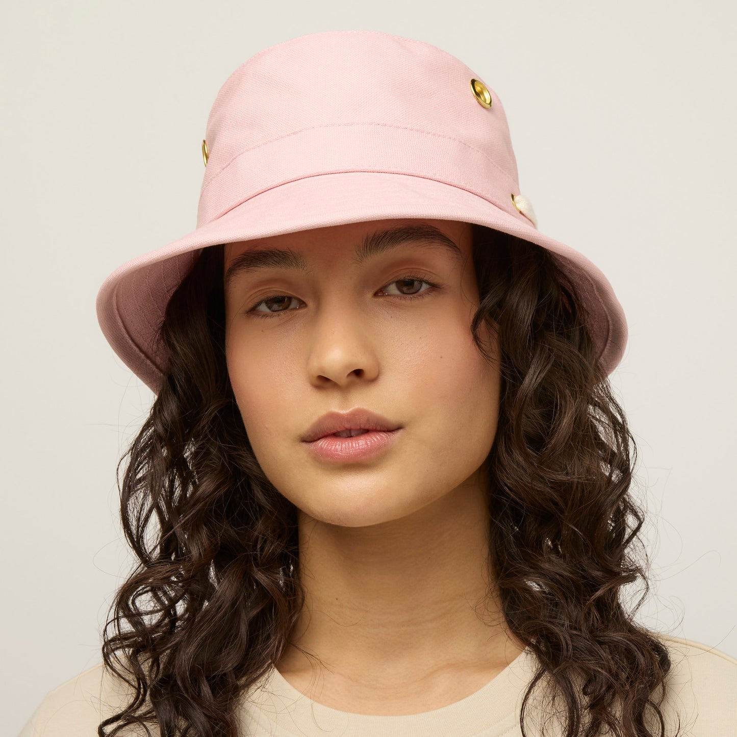 Woman with long curly hair wears a light pink Tilley T1 Iconic Bucket Hat, offering sun protection.