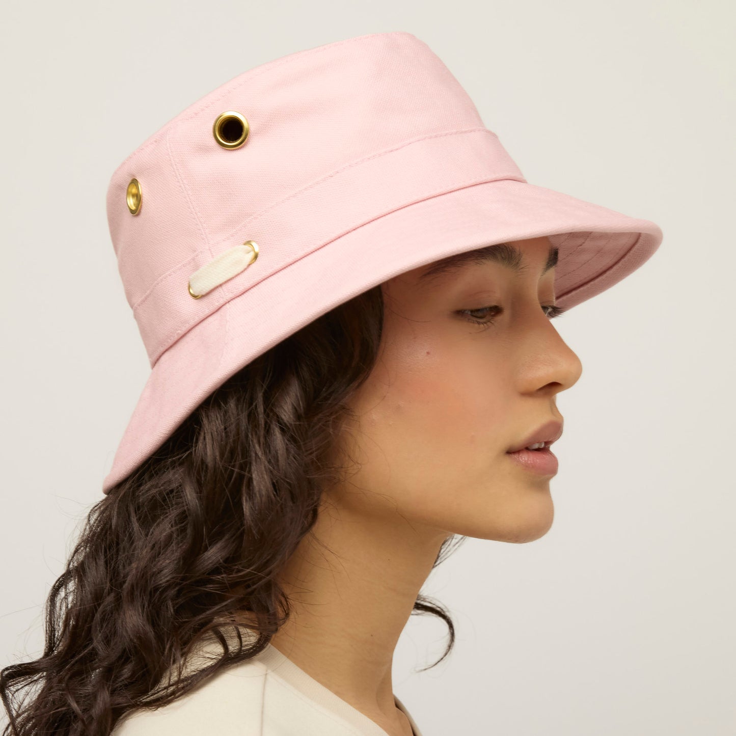 Person in profile wears a Tilley T1 Iconic Bucket Hat in pink with metal eyelets.