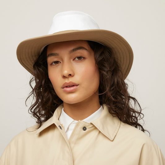 Product Image – Person with long, wavy hair wears a beige coat and the Tilley LTM6 Airflo® Contrast Broad Brim Hat for sun coverage.
