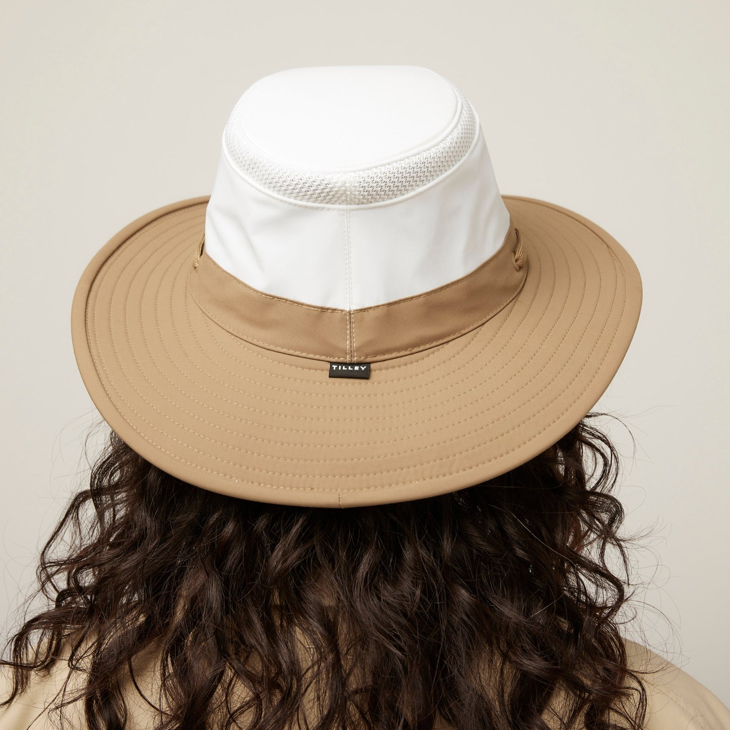Person with long curly hair in a Tilley LTM6 Airflo® Contrast Broad Brim Hat, seen from behind.