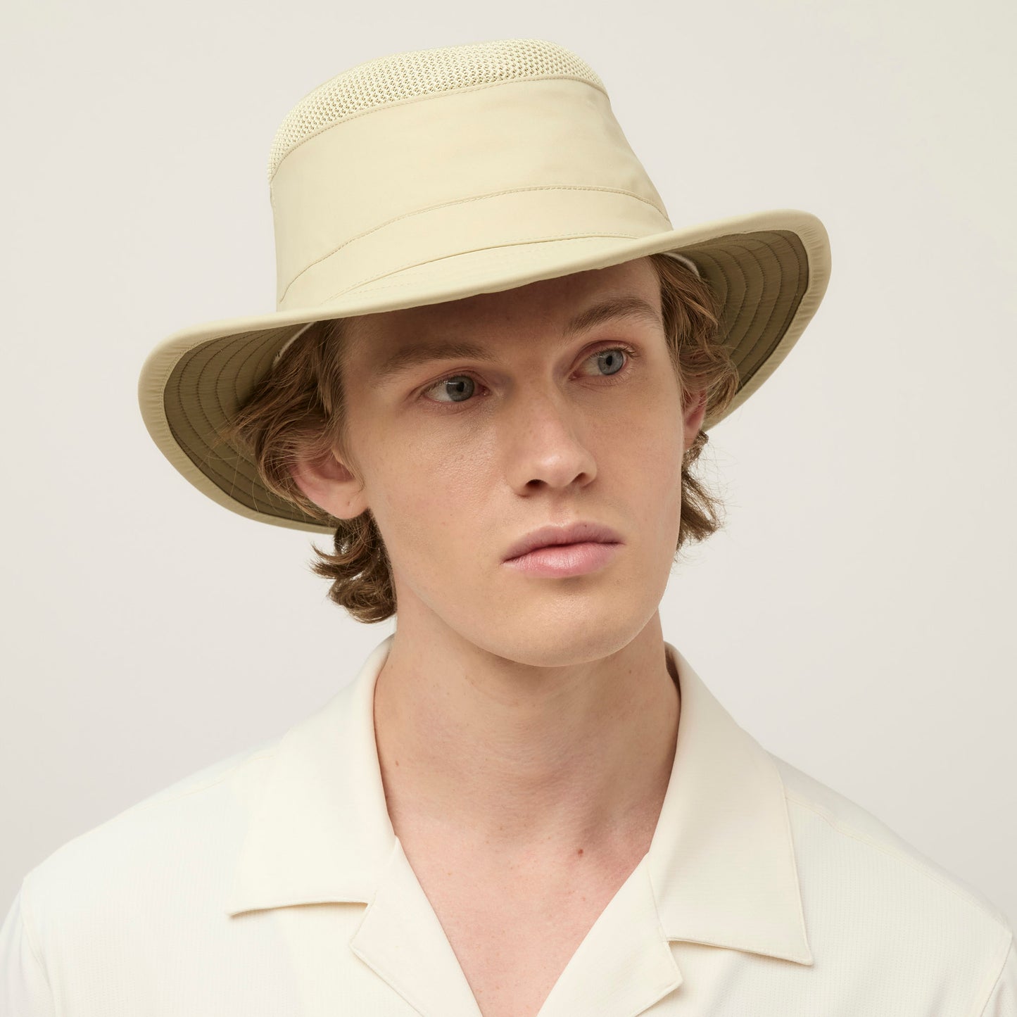 A young man in a Tilley LTM5 Airflo® Hat and light shirt looks slightly to the side against a plain background.