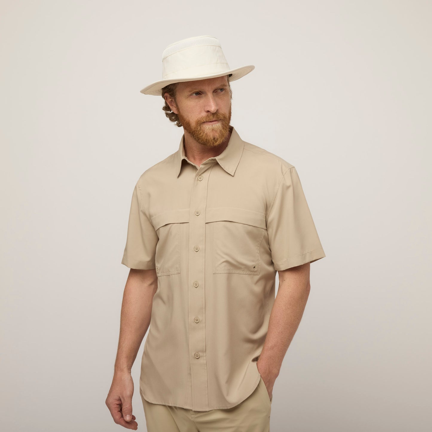 A man in a beige UPF 50+ shirt and a Tilley Airflo® Boonie Hat stands against a light background.