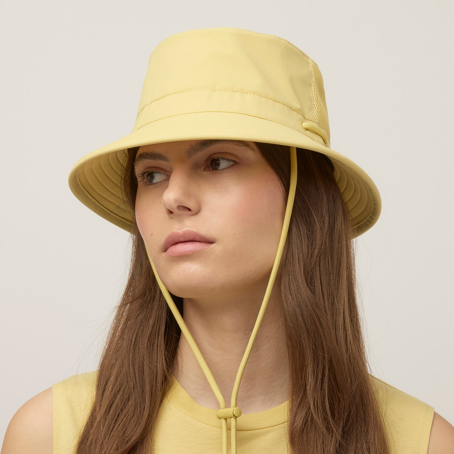 Person in a Tilley LTM1 Airflo® Bucket Hat and matching sleeveless top, looking to the side.