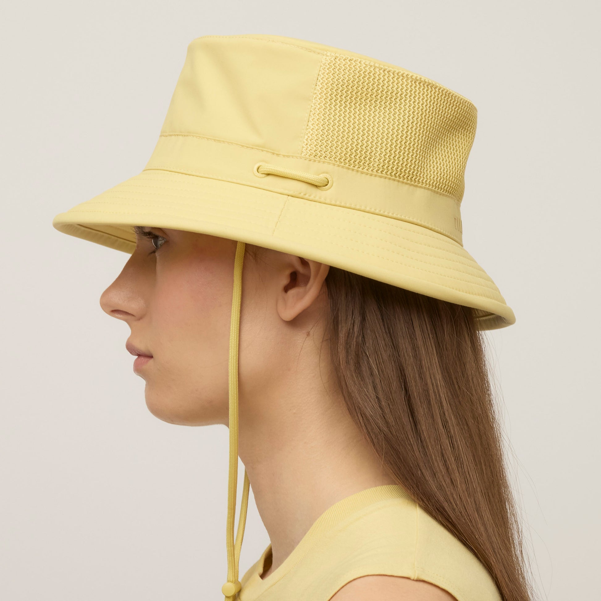 A woman in profile wears the Tilley LTM1 Airflo® Bucket Hat with a chin strap and mesh side panel.