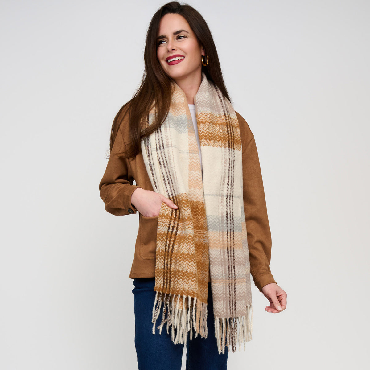 A woman wearing a Howard’s Taupe Plaid Fringe Scarf in buttery soft, taupe and brown tartan with fringe ends.