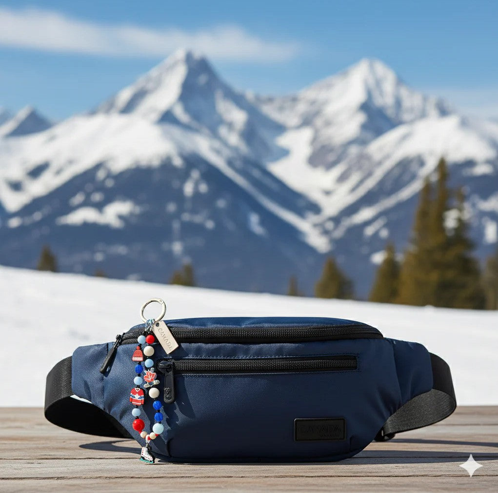 A blue waist pack with a Northern Icons Hockey North Beaded Bag Charm rests on wood; snowy peaks behind.