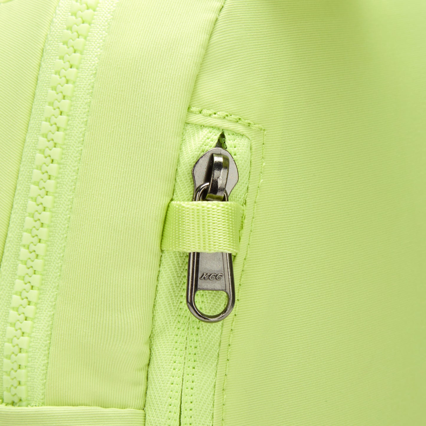 Close-up of the matcha green Pacsafe® CX Anti-theft 8L Backpack Petite featuring a metal zipper pull and security loop.