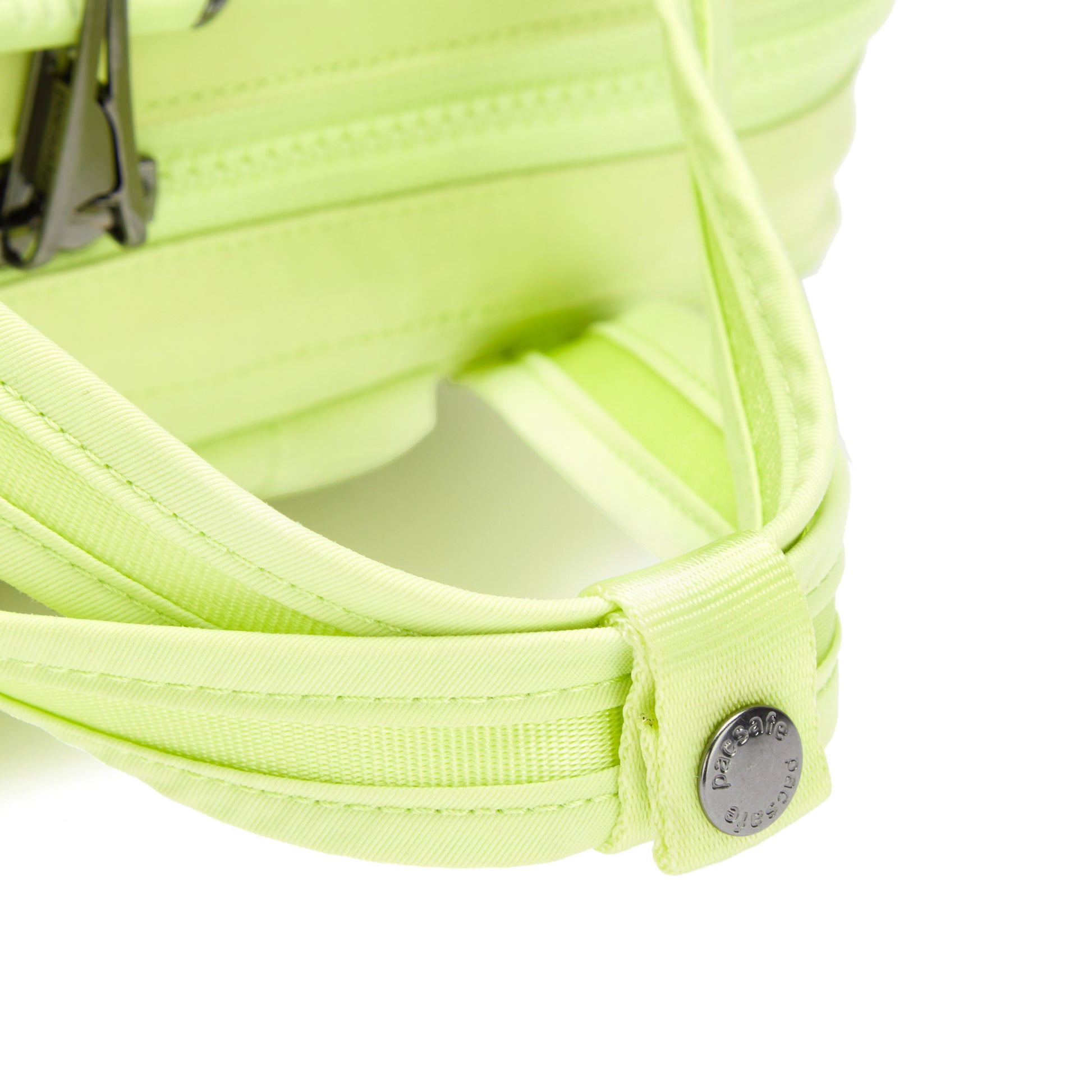 Close-up of the Pacsafe® CX Anti-theft 17L Backpack, a matcha green recycled polyester bag with metal buckles and logo tag.