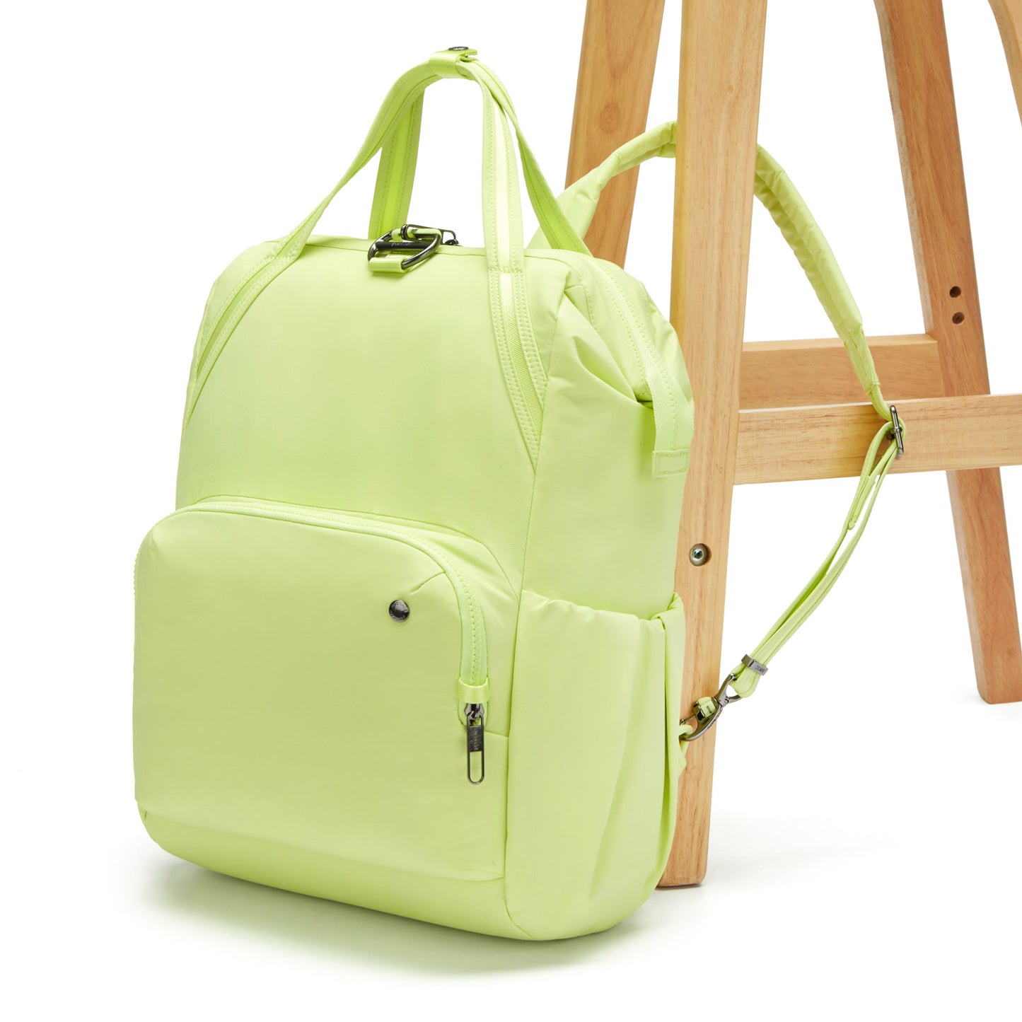 A matcha green Pacsafe® CX Anti-theft 17L Backpack hangs on a wooden ladder.