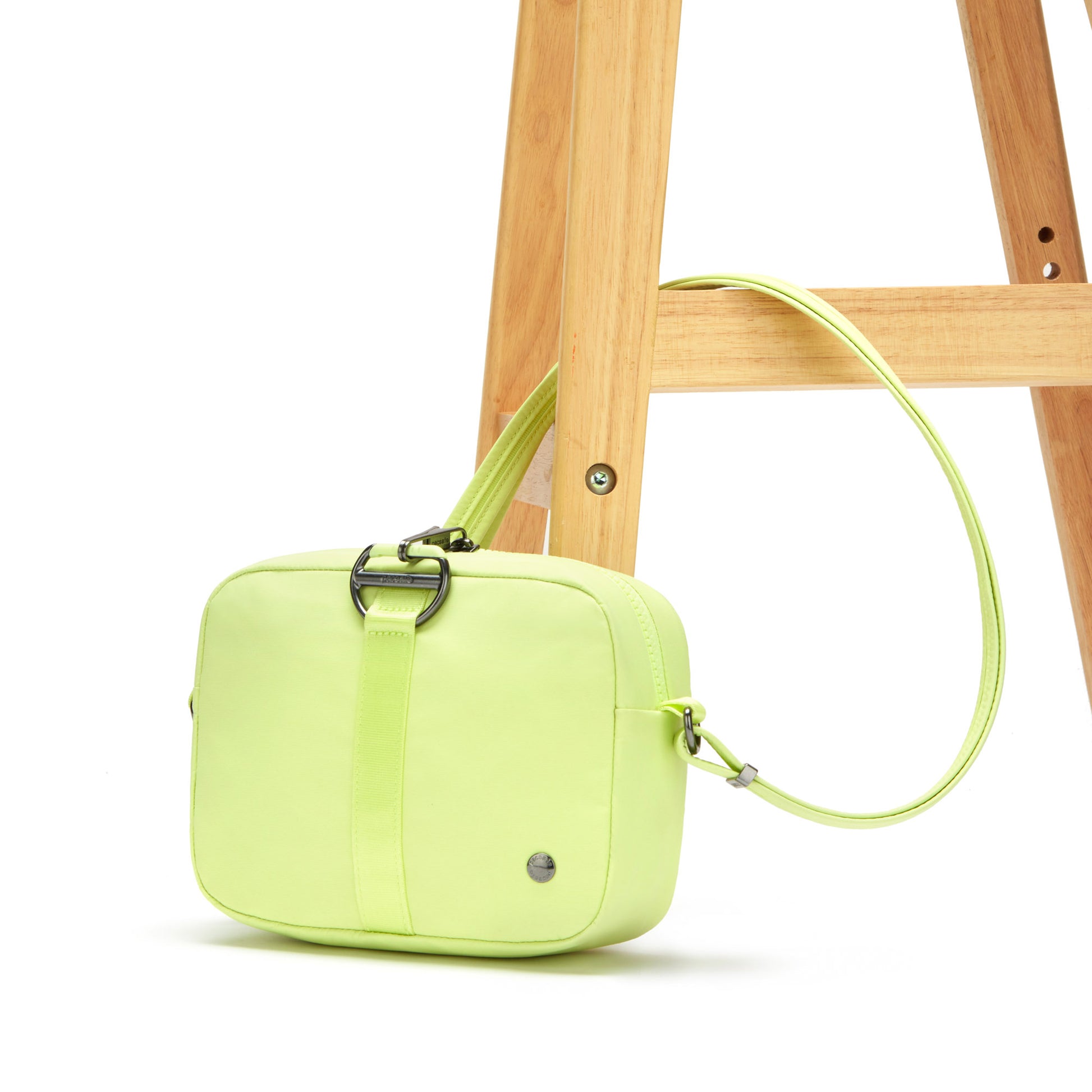 Pacsafe® CX Anti-theft Square Crossbody, matcha, secured to a wooden chair leg.