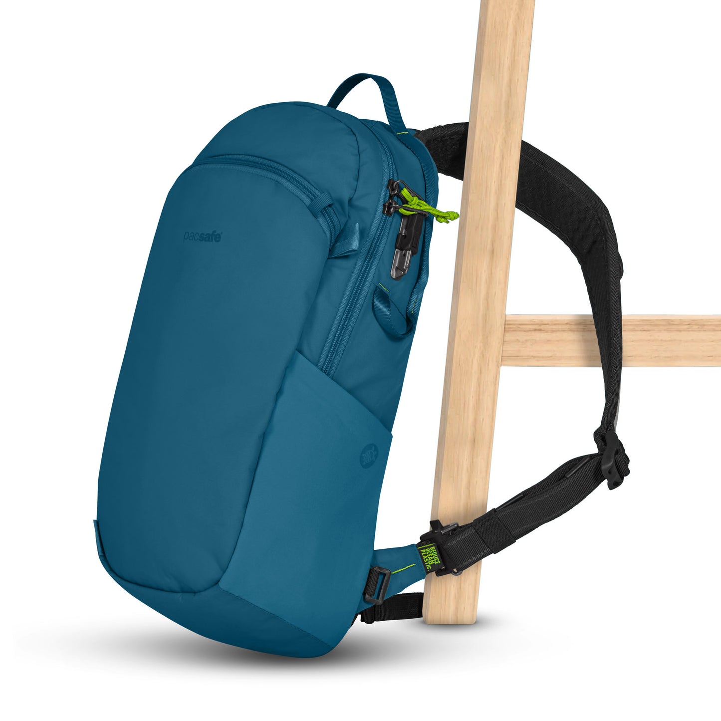 Pacsafe® ECO 12L Anti-theft Sling Backpack in teal with black straps and green accents, against wooden chair.