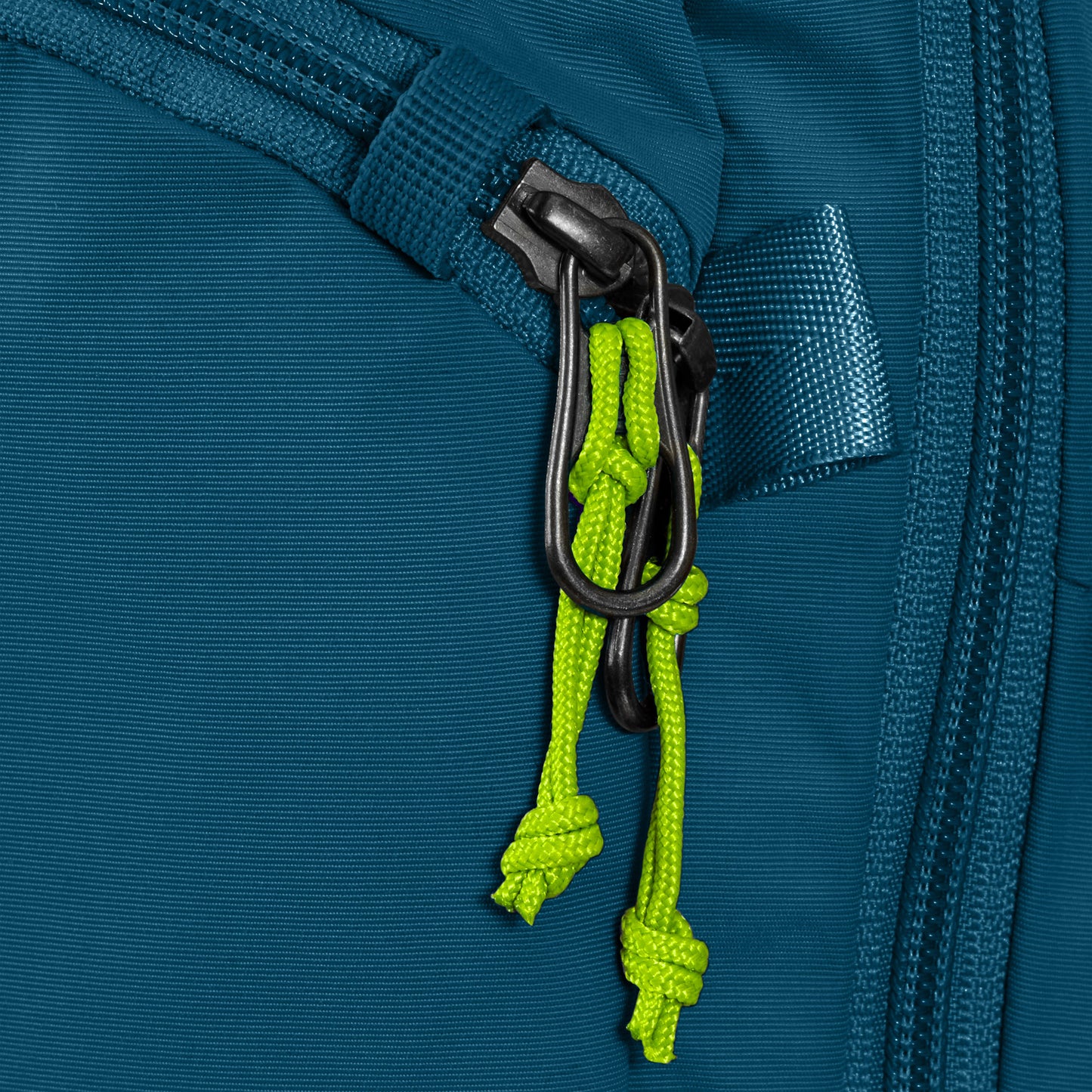 Close-up of the Pacsafe ECO 12L Anti-theft Sling Backpack zipper with green cord pulls.