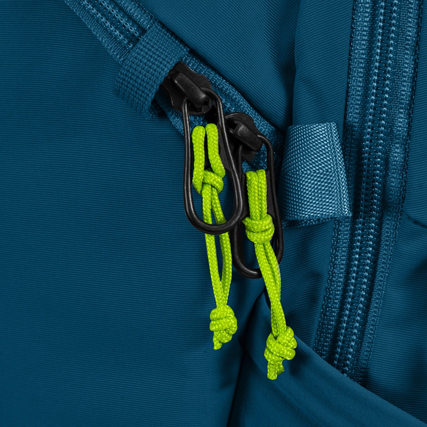 Close-up of Pacsafe ECO 18L Anti-theft Backpack zipper with green pulls on ECONYL® regenerated nylon teal fabric.