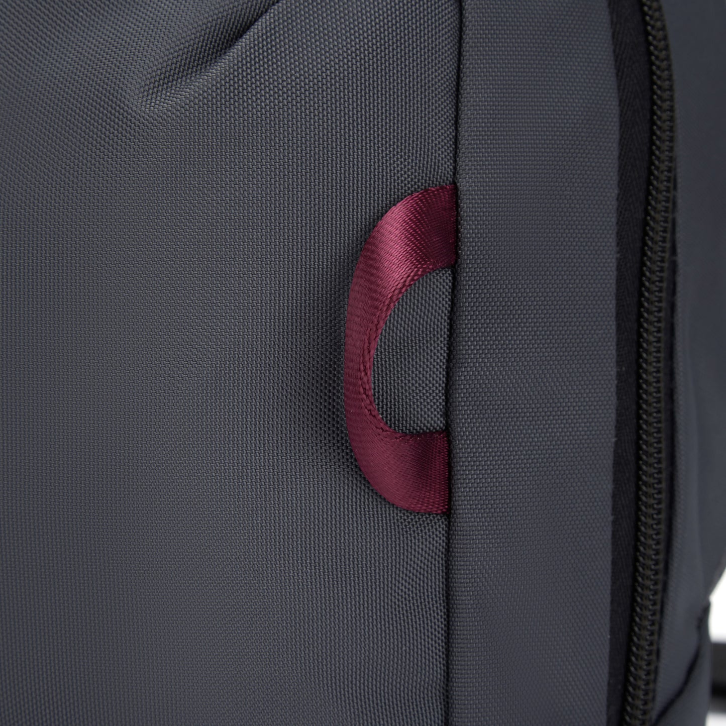 Close-up of the Pacsafe® EXP 12 Sling Crossbody in slate with burgundy side lashing point.