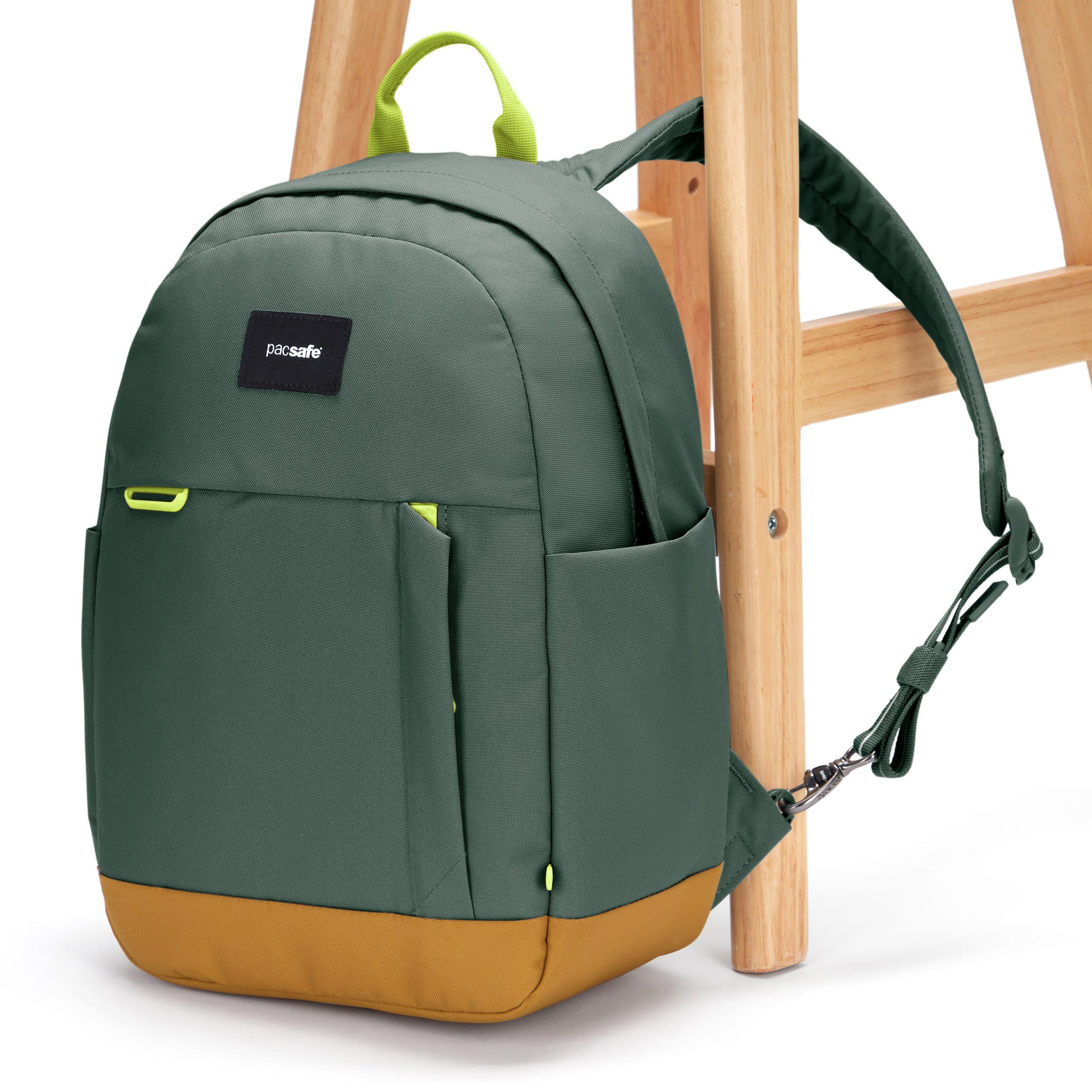 Pacsafe® Go 15L Anti-theft Backpack, spruce green with tan bottom gusset, attached to a chair leg