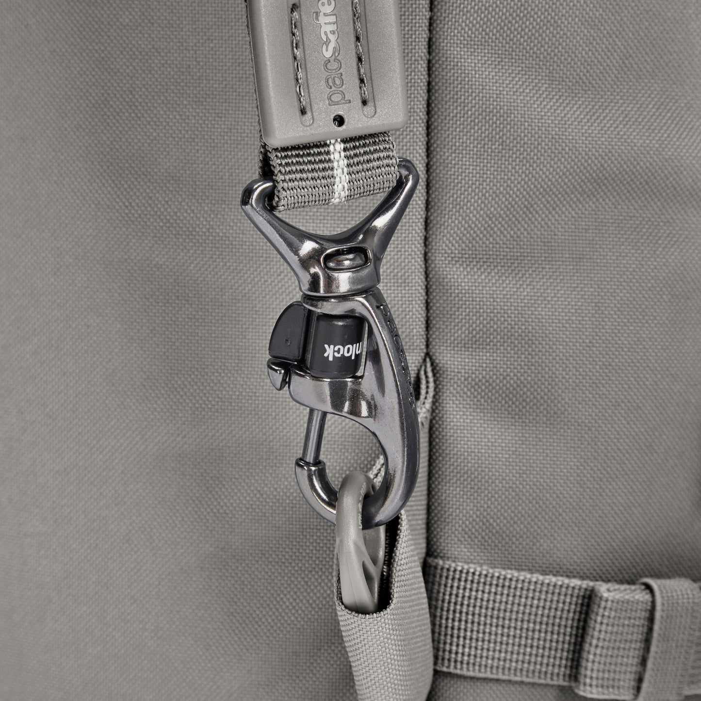 Close-up of a metal lock latch on Pacsafe® GO 34L Anti-theft Carry-on Backpack’s gray recycled polyester strap.