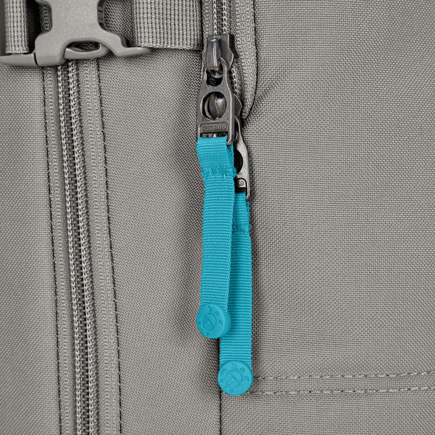 Close-up of the Pacsafe® GO 34L Anti-theft Carry-on Backpack, gray with two zippers and blue pull tabs.