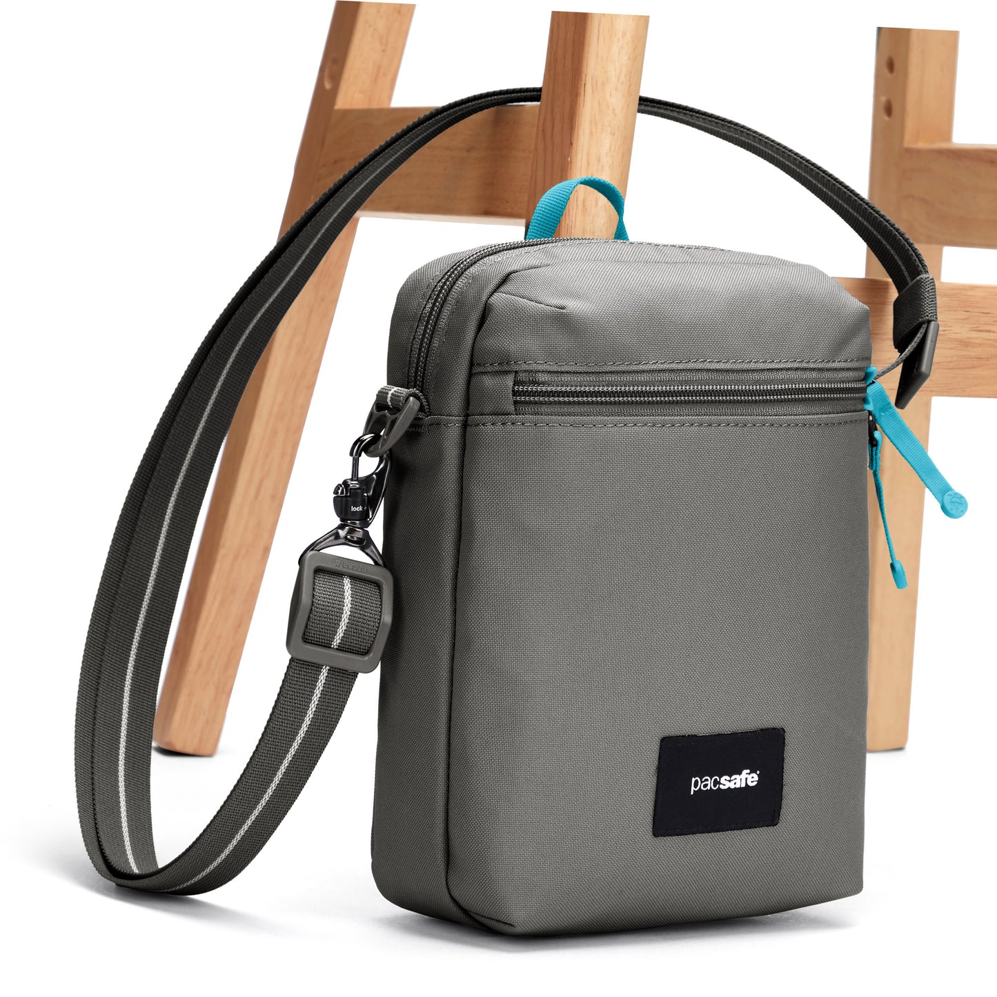 Pacsafe® GO Anti-Theft Festival Crossbody, stone, with crossbody strap affixed through a wooden chair leg.