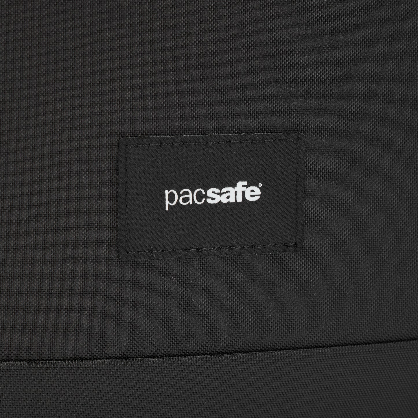 Close-up of black recycled polyester with stitched Pacsafe® label on the Pacsafe® GO 15L Anti-theft Totepack.