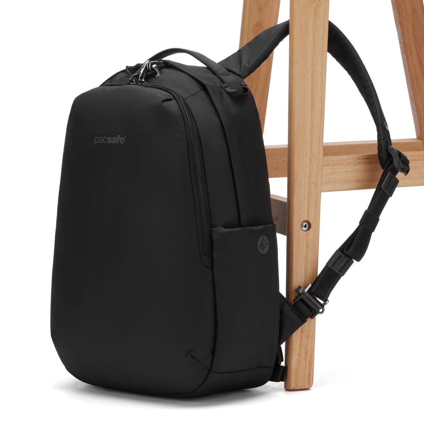 The Pacsafe® V 16L anti-theft backpack in black, made from recycled polyester, is secured to a wooden chair.