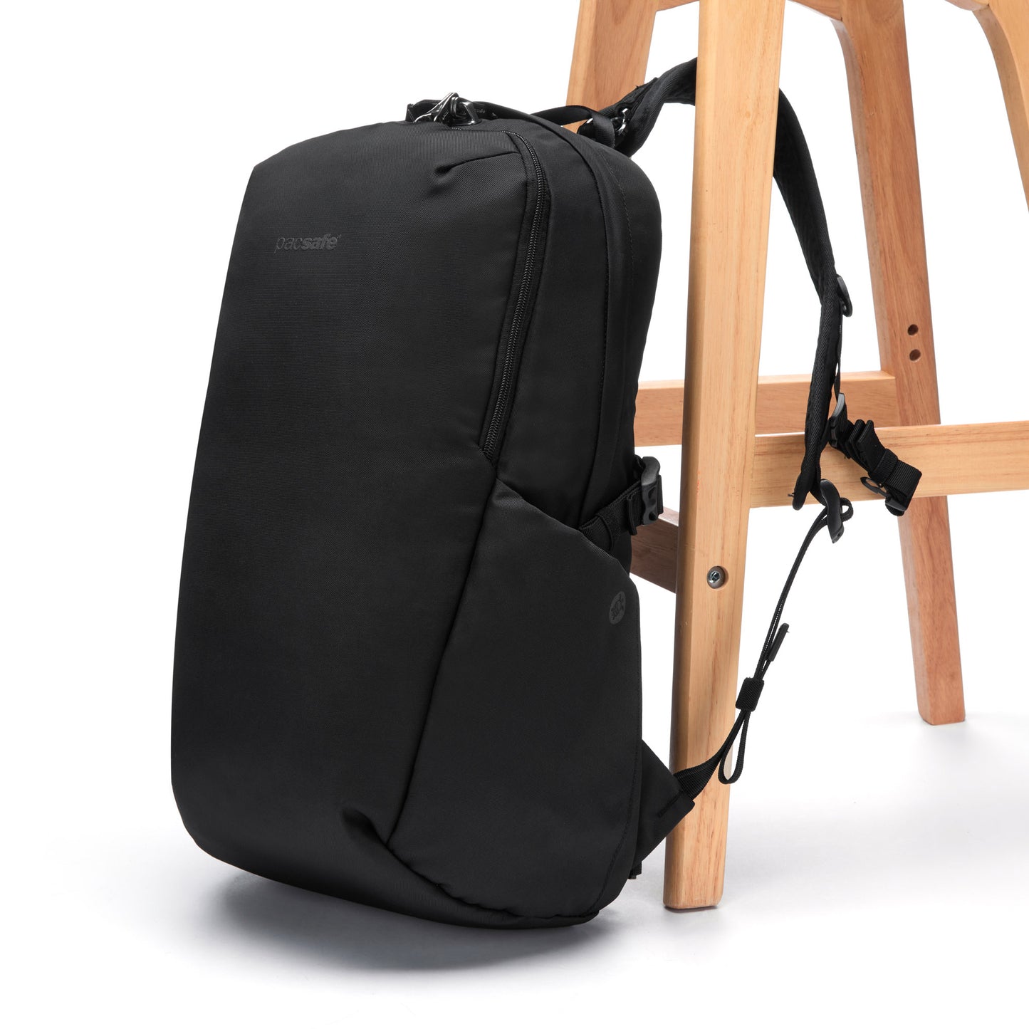 Pacsafe® V 24L Anti-theft Active Backpack with laptop sleeve against a wooden chair on white background.