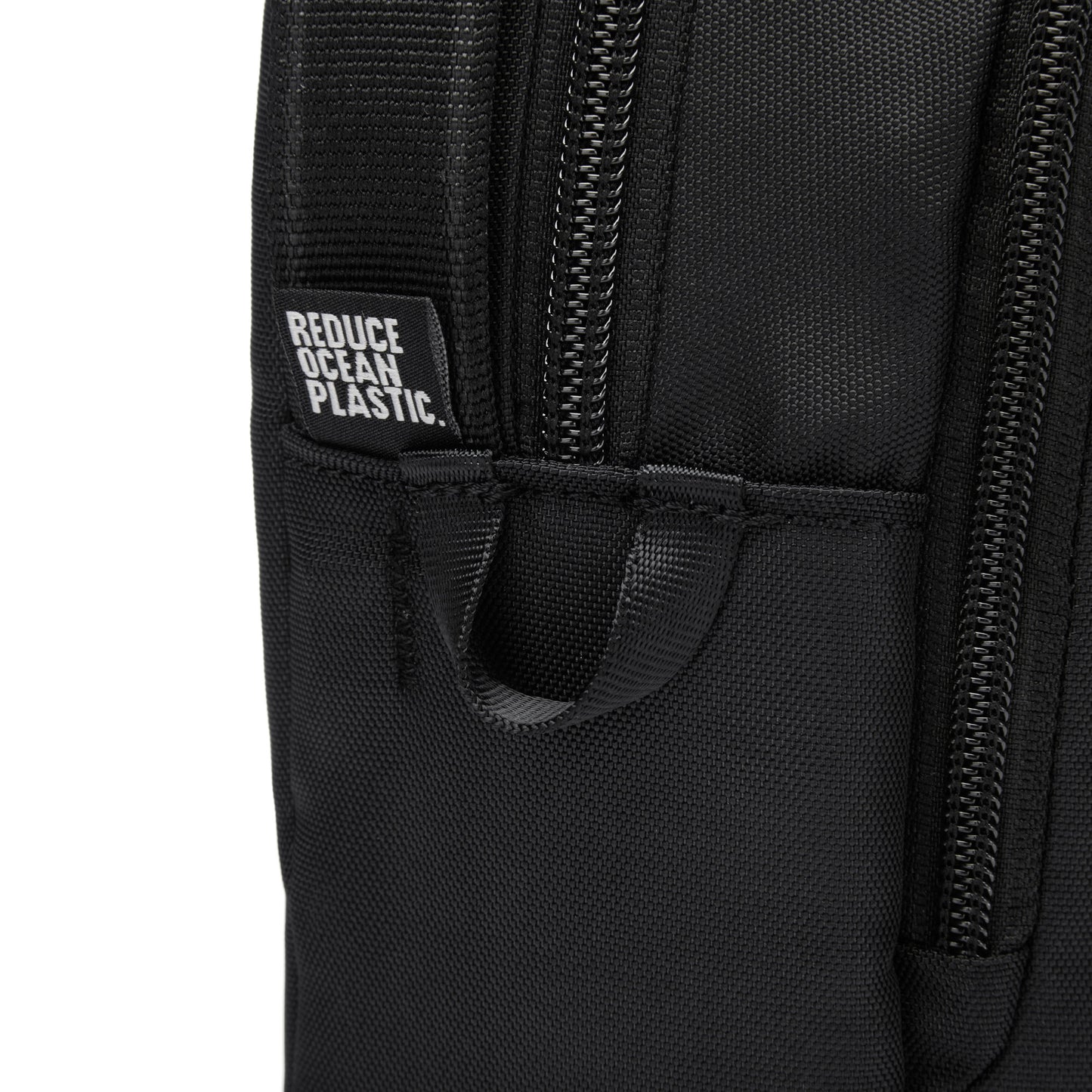 Close-up of Pacsafe® V Anti-theft Crossbody in recycled polyester with "Reduce Ocean Plastic" label near the zipper.
