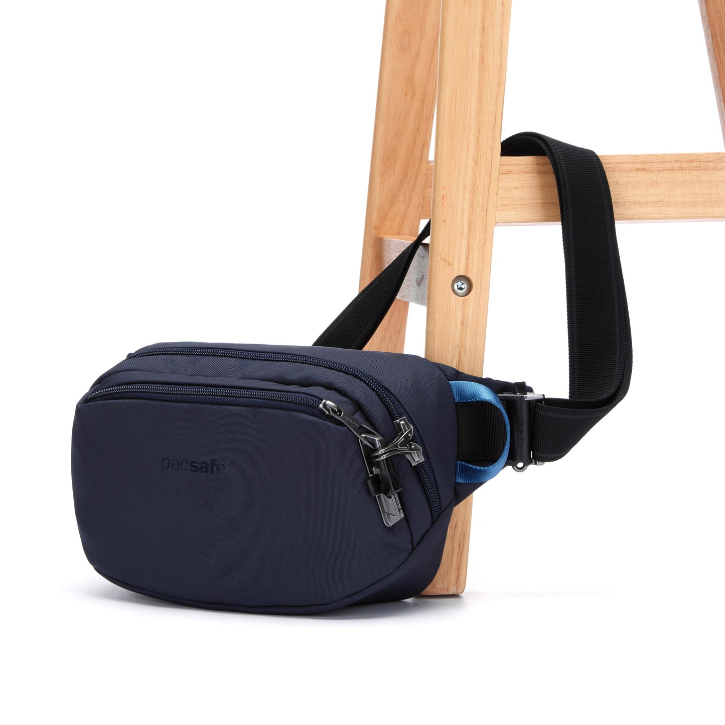 Pacsafe® V anti-theft hip pack in ocean blue secured to a wooden chair leg.