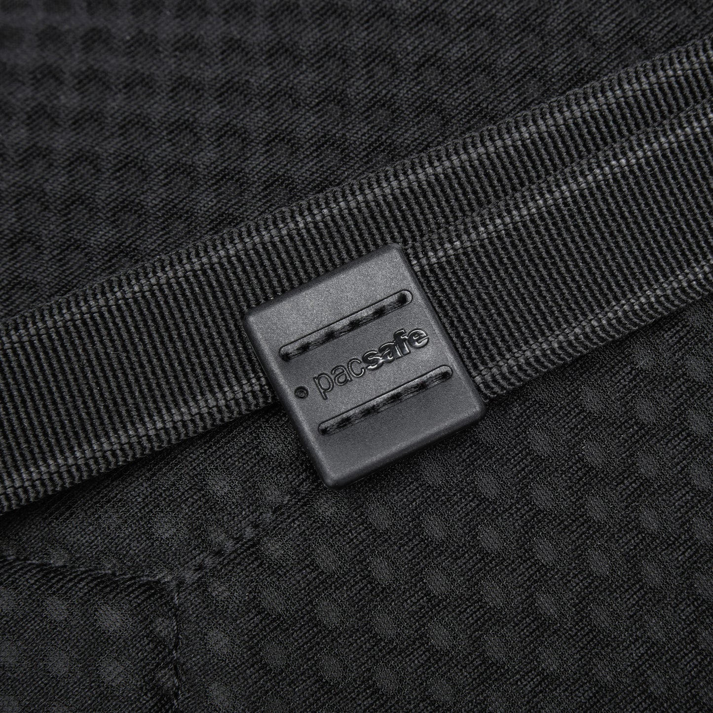 Close-up of a black Pacsafe® V Tech Anti-theft Sling Pack strap against a textured background.
