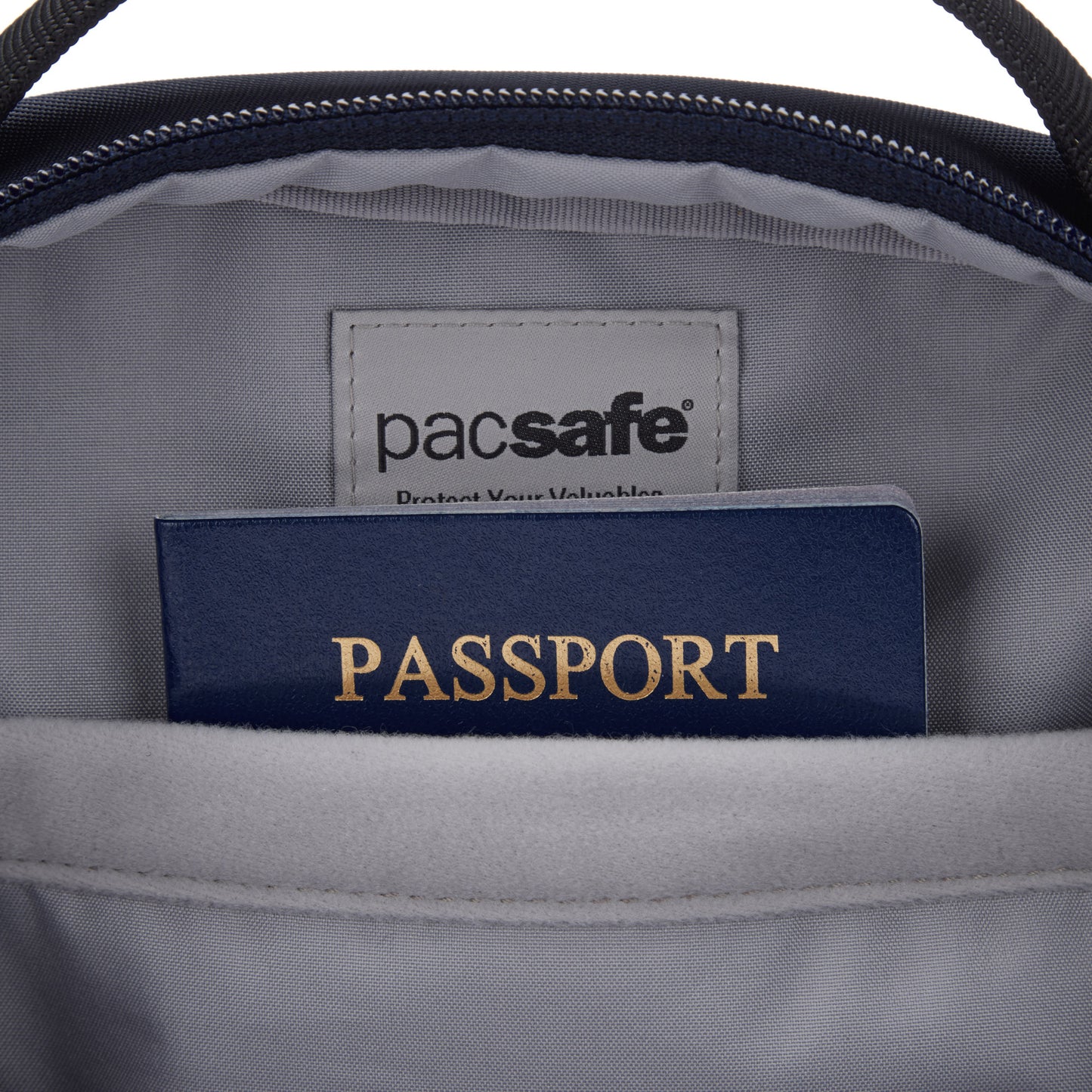 A passport peeks from a Pacsafe® V Anti-theft Tour Crossbody's lockable compartment.