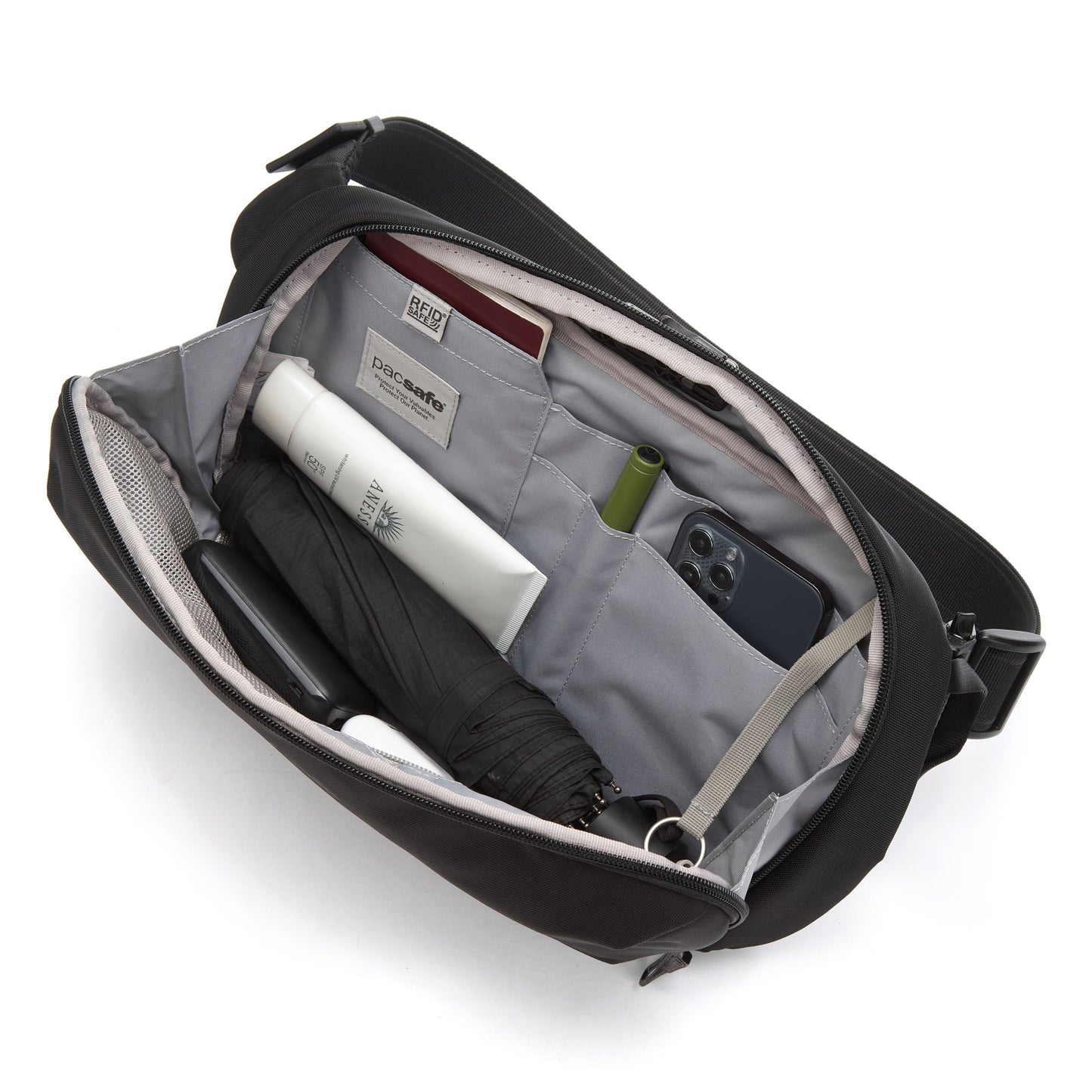 Open the Pacsafe® V Sling to reveal an umbrella, phone, book, pen, tube, and an anti-theft zipper pocket.