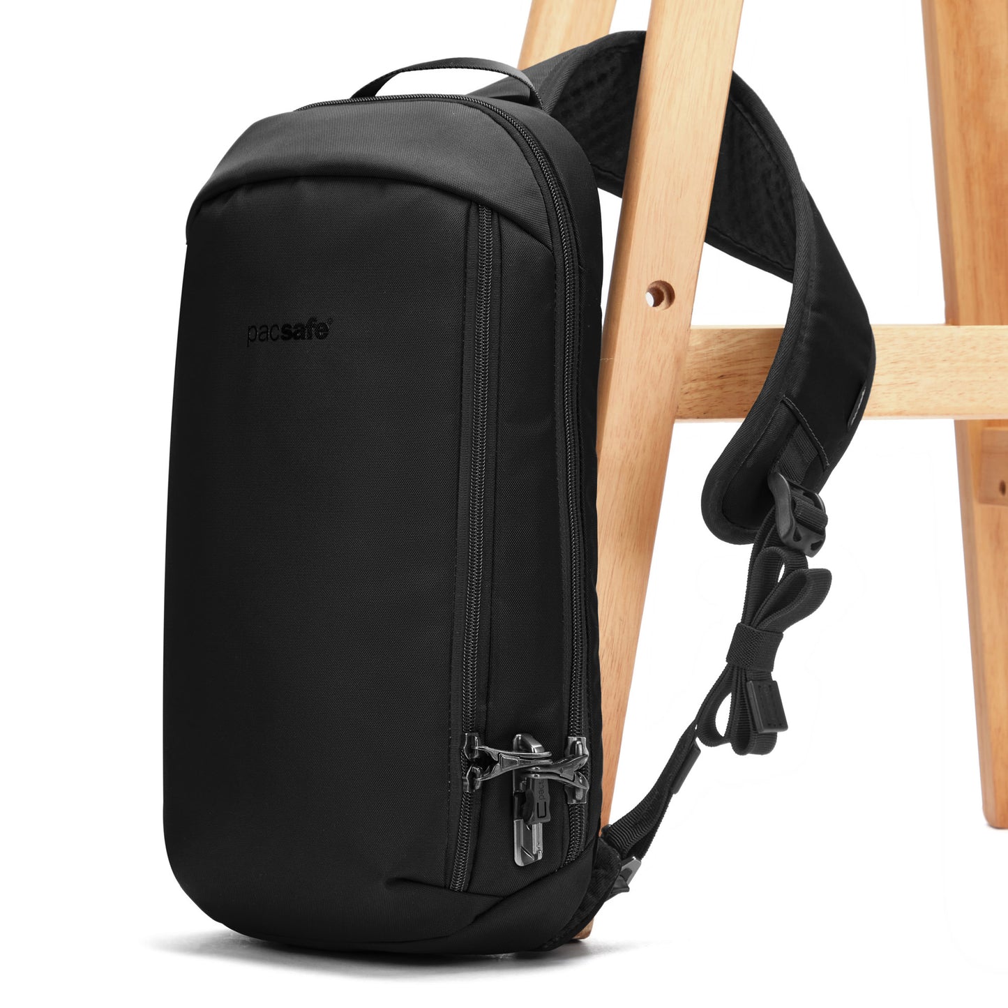 Pacsafe® V Tech Anti-theft Sling Pack with padded straps and front pocket attached to a wooden chair.