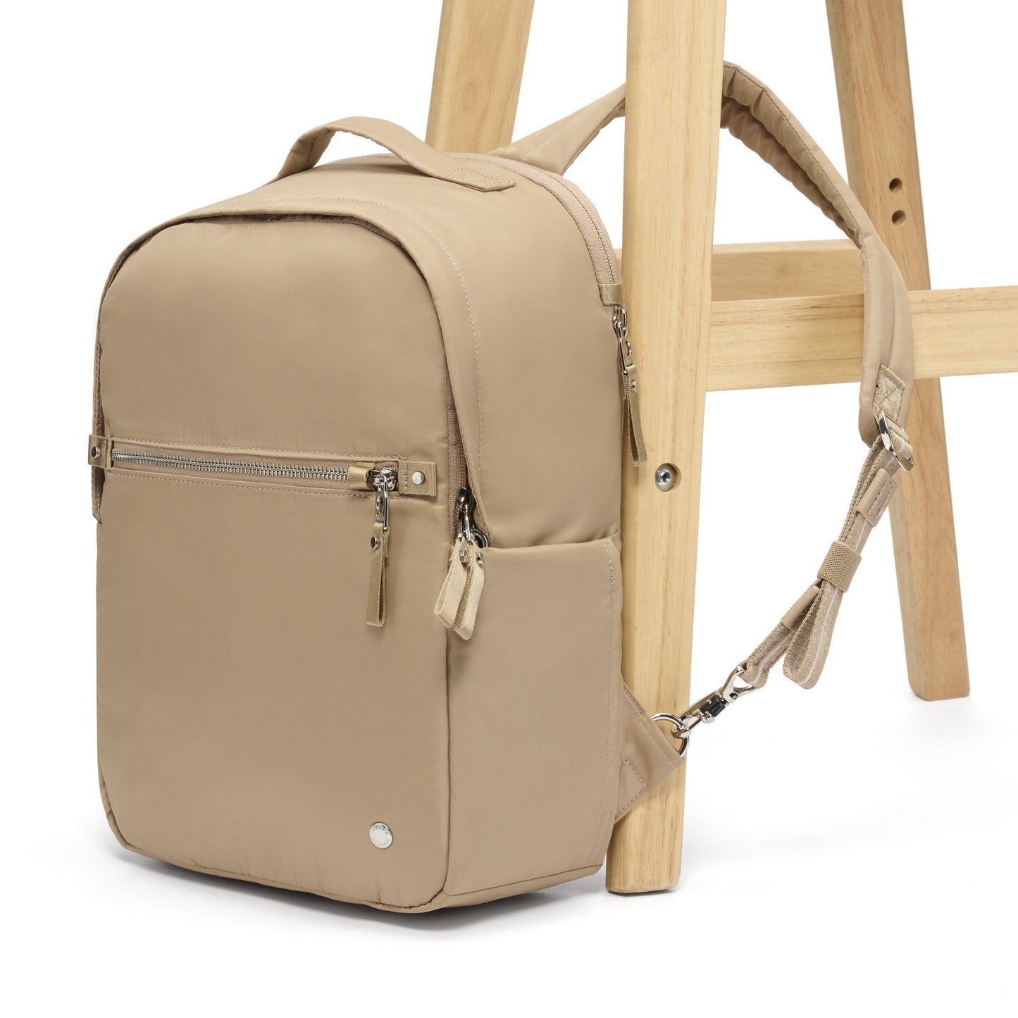 The Pacsafe® W 10L Anti-theft Backpack, taupe, attached to chair leg.