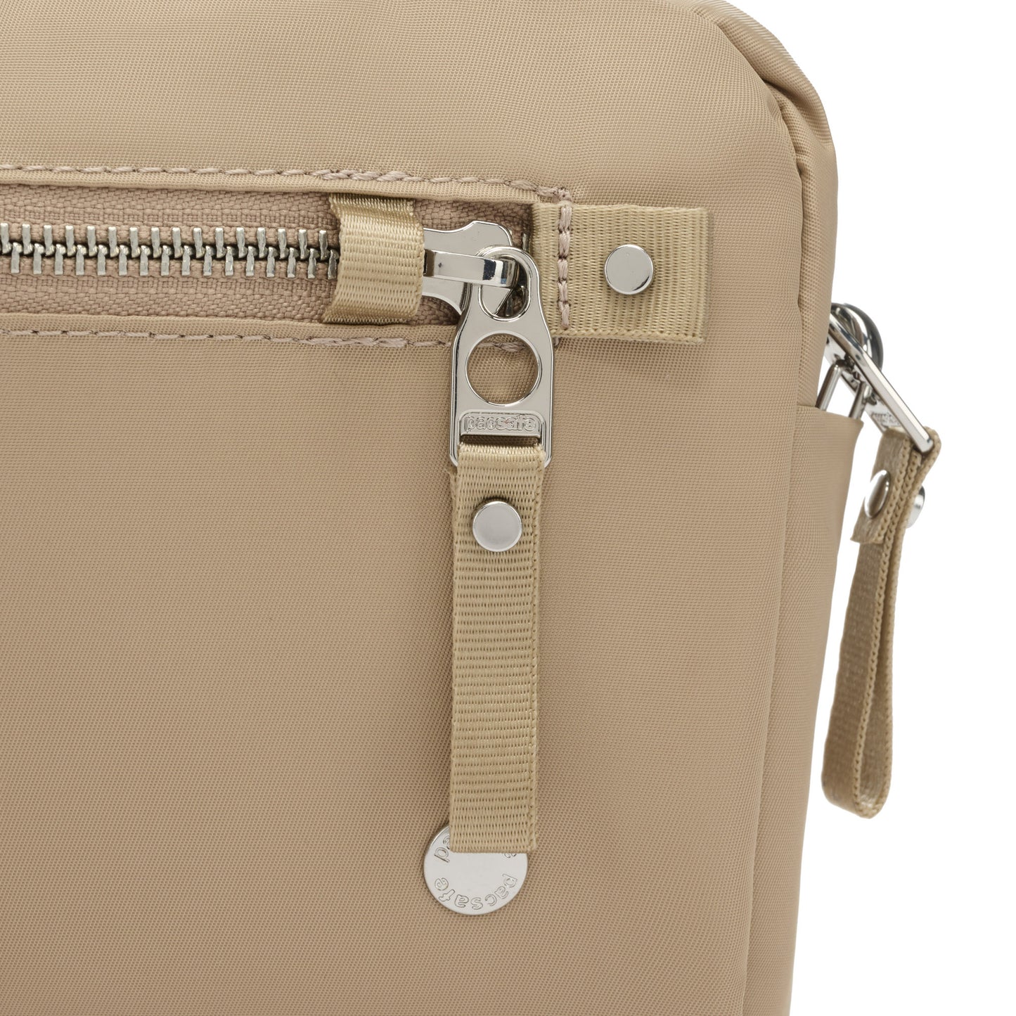 Close up of taupe and silver zipper pull and security loop on Pacsafe® W Anti-theft 3-in-1 Sling