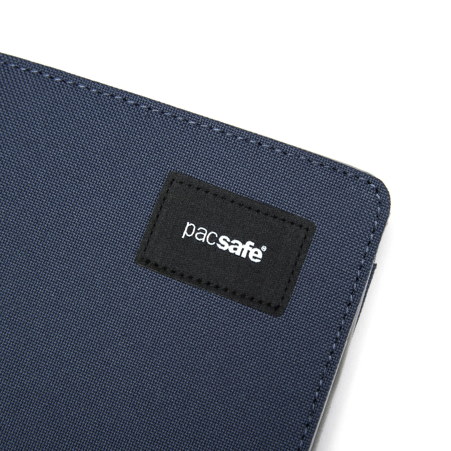Close-up of a blue fabric corner with a black "Pacsafe" label from the RFIDsafe™ RFID Blocking Bifold Wallet.