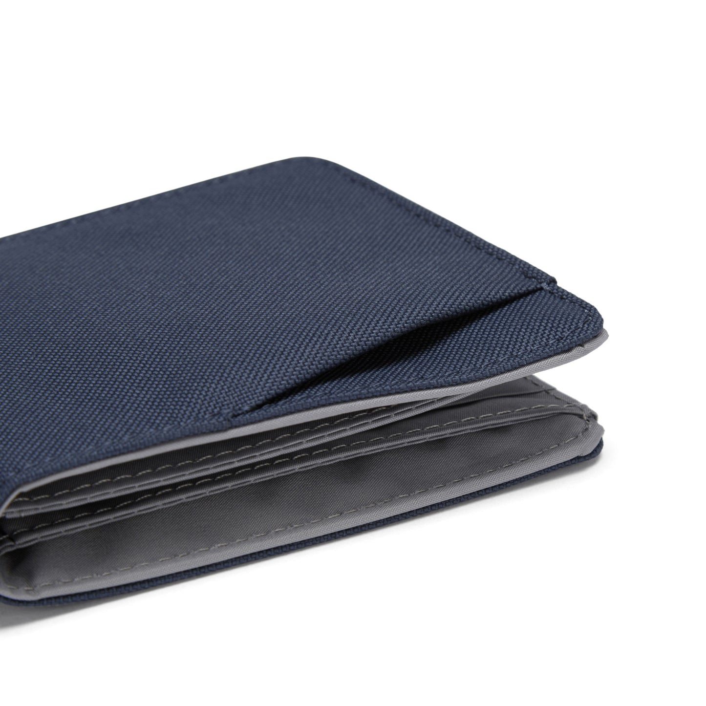 A slim blue Pacsafe® RFIDsafe™ wallet made of recycled polyester with a visible edge on white.