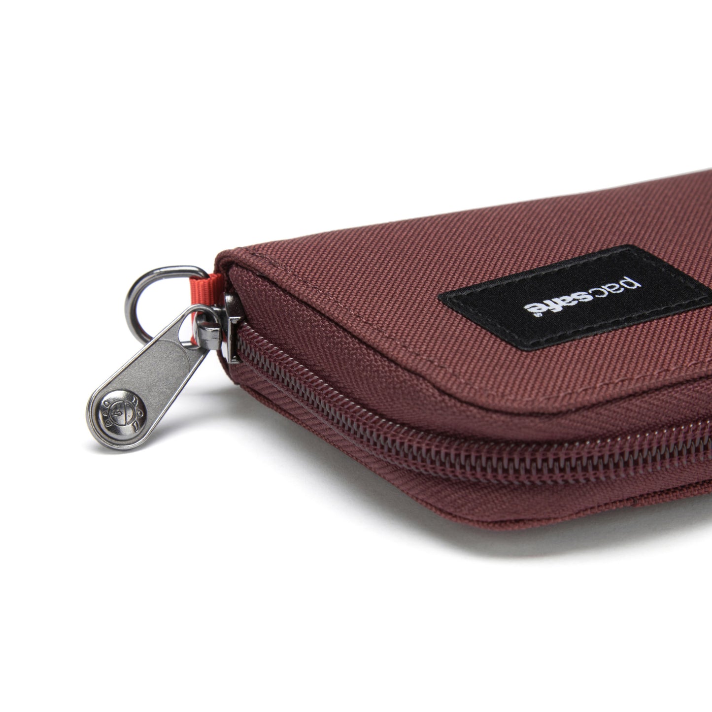 A garnet red Pacsafe pouch with a silver zipper and black label, made from recycled polyester.