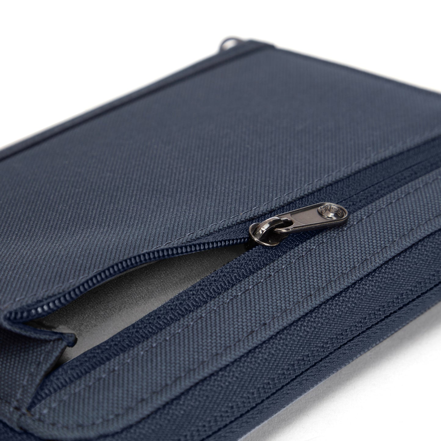 Close-up of a partially open Pacsafe® RFIDsafe™ navy RFID blocking travel organizer on a white background.