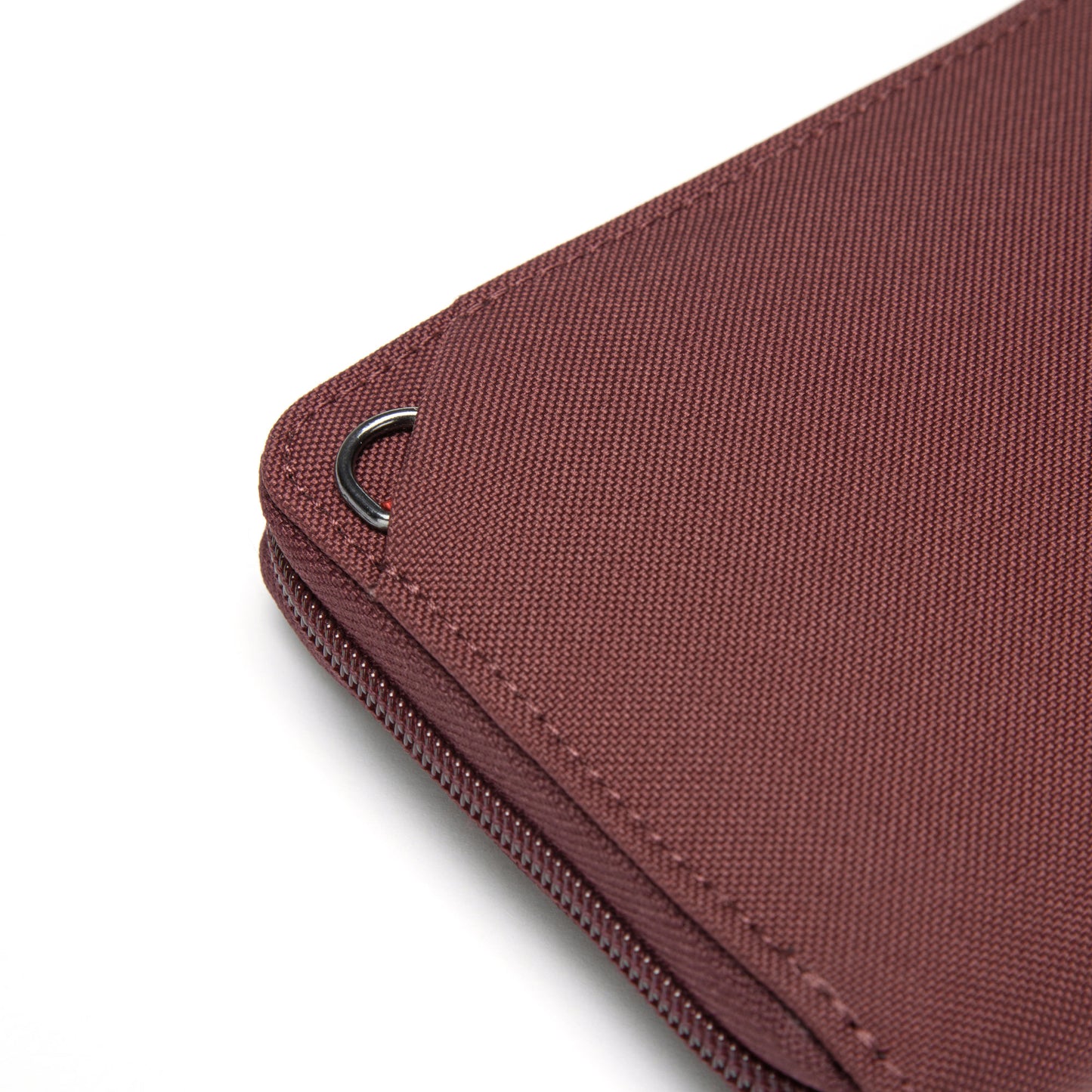 Close-up of a Pacsafe® RFIDsafe™ Wallet corner, garnet red with RFID-blocking and a black metal hook attached.