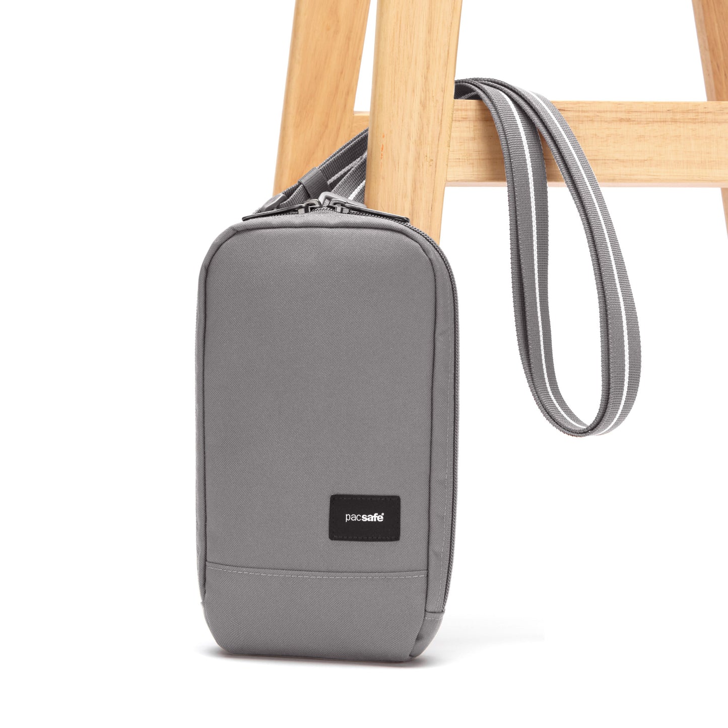 Pacsafe® RFIDsafe™ RFID Blocking Tech Crossbody, stone, affixed to a wooden chair leg.
