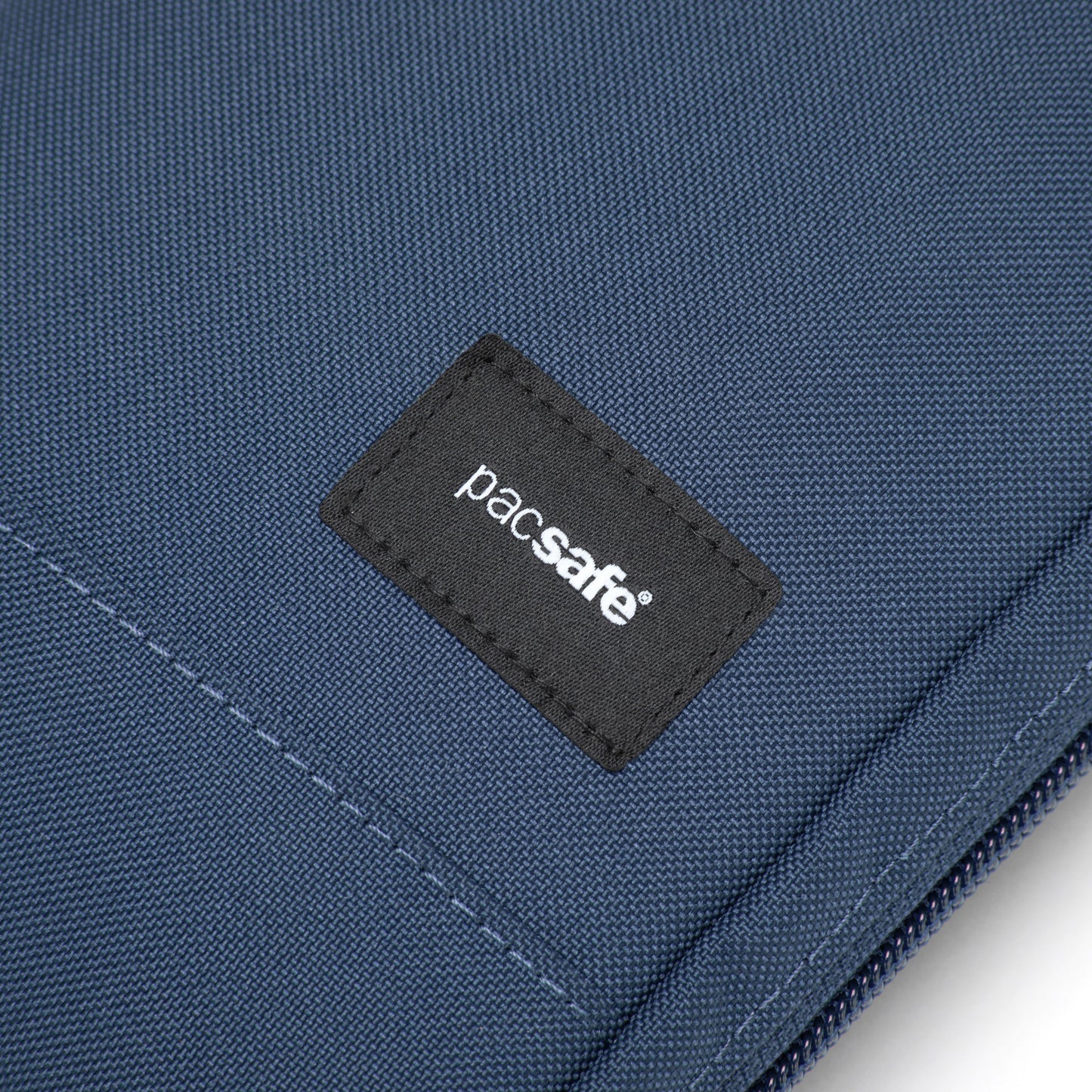 Blue RFID-blocking fabric close-up with a black "Pacsafe" label from the Pacsafe® RFIDsafe™ Crossbody.
